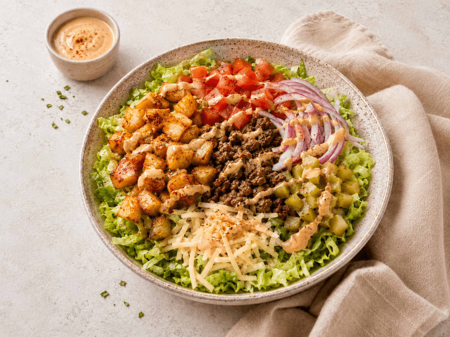 Cheeseburger salad bowl with beef mince, crispy potatoes, lettuce, tomato and burger sauce