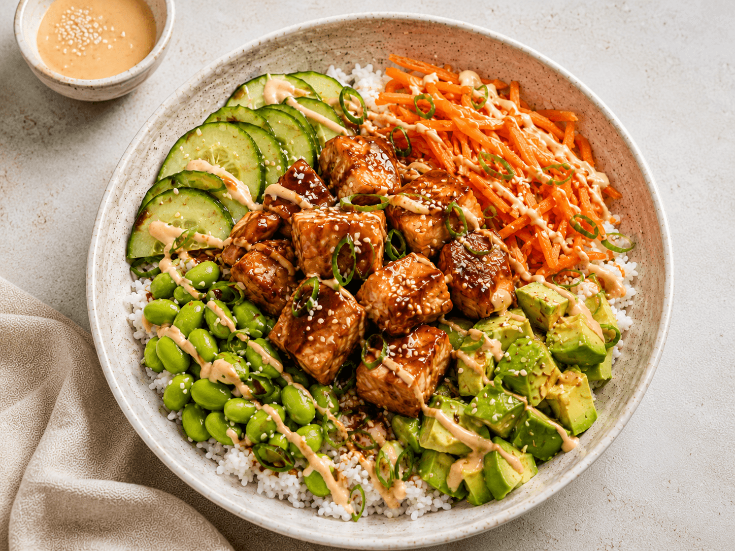 Teriyaki salmon rice bowl with cucumber, carrot, edamame, avocado and sriracha yoghurt drizzle