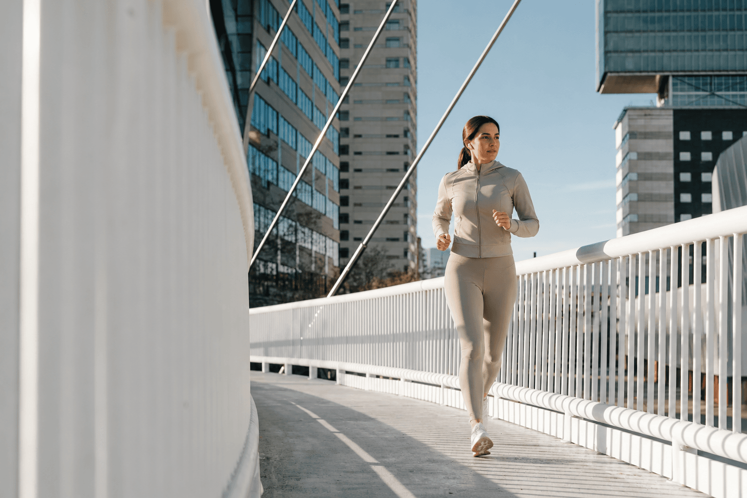 Person jogging on a bridge in an urban setting, representing cardio and daily movement